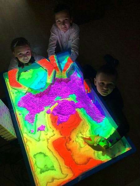 Børn leger med en sandkasse, som er med en masse flotte farveprojektioner