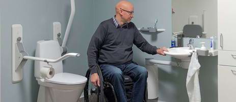 Mand i kørestol mellem toilet og vask