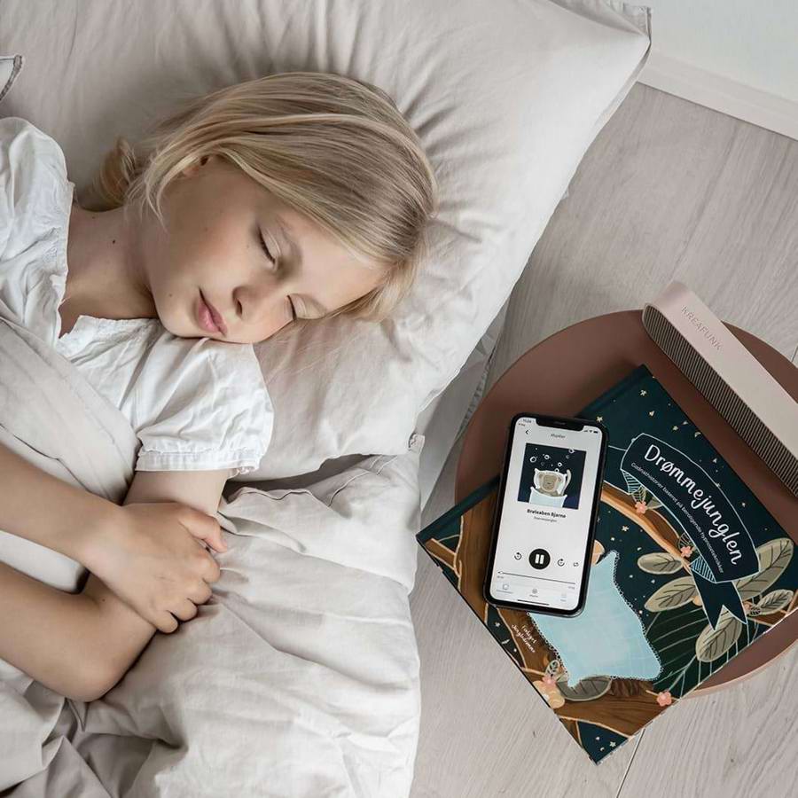 Barn ligger i senge og lytter til appen Drømmejunglen