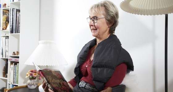 Kvinde sidder og læser med kraven over skuldre og overkrop